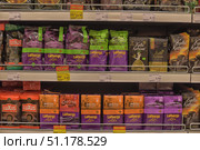 Supermarket shelf with packages of ground coffee of various brands. In the center, Löfbergs Lila coffee bags in characteristic purple and green packaging (Medium Roast, Prezzo, Kharisma) are clearly visible, presented in 250 and 500 gram packages. On the right are Kulta Katriina coffee packs in black and gold packaging, as well as in bags with images of coffee cups. On the left, red packages of Luxus coffee are visible on the shelf. All the products are neatly lined up in rows, and under them are price tags and promotional labels Hea Hind (Good Price). The atmosphere of the photo conveys the view of the grocery department of the supermarket, where a wide range of coffee is offered for customers with different preferences. (2015 год). Редакционное фото, фотограф Анна Кривицкая / Фотобанк Лори