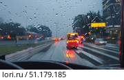 A driver navigates a busy city during a rainy evening, with colorful lights and reflections on the wet pavement. Стоковое AI-видео, аниматор Данила Большаков / Фотобанк Лори