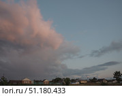 Large beautiful cumulus clouds in evening sunset sky over rural area with houses, summer landscape. Стоковое фото, фотограф irisff / Фотобанк Лори
