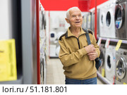 elderly grayhaired man pensioner looking washing machine at counter in showroom of electrical appliance hypermarket department. Стоковое фото, фотограф Татьяна Яцевич / Фотобанк Лори