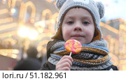 Child with lollipop in his hand walking through city decorated for Christmas holidays. Стоковое фото, фотограф Маргарита Кирьякова / Фотобанк Лори