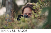 Female wildlife photographer hiding in bushes, capturing nature through camera lens with intense focus, surrounded by natural foliage in an outdoor forest setting. Стоковое AI-изображение, AI-художник Катерина Бондарец / Фотобанк Лори