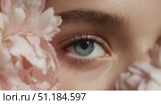 Close-up of beautiful blue eye framed by soft pink flowers showcasing natural beauty and serenity in a tranquil setting. Стоковое AI-видео, аниматор Ekaterina Ismagilova / Фотобанк Лори