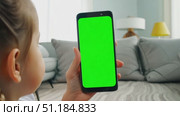 A young girl interacts with a blank smartphone screen in a bright and inviting living room setting. Стоковое AI-видео, аниматор Данила Большаков / Фотобанк Лори