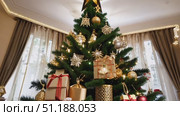 A family gathers in a cozy living room to decorate a Christmas tree adorned with shiny ornaments and beautifully wrapped gifts. Стоковое AI-видео, аниматор Данила Большаков / Фотобанк Лори