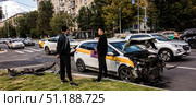 Мужчина держит паспорт и страховой полис. Аварии, катастрофы на дорогах. Дорожно-транспортное происшествие с участием такси. Повреждённый автомобиль, разбитый, обломки. Водители обсуждают вопросы денежной компенсации. Москва, 2025/ Редакционное фото, фотограф Iva Noel / Фотобанк Лори