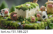 A whimsical scene featuring miniature cows made of soft materials around a block of butter labeled 'MILK'. The setting is lush with green moss and small flowers. Стоковое AI-видео, аниматор Ekaterina Ismagilova / Фотобанк Лори
