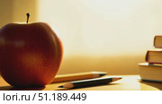 Bright sunlight filters through, highlighting stacked books with a pencil and an apple nearby, creating a warm study environment perfect for learning. Стоковое AI-видео, аниматор Данила Большаков / Фотобанк Лори