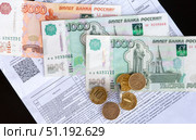 Бумажные купюры и монеты лежат на квитанции оплаты жилищно коммунальных услуг. Стоковое фото, фотограф Анищенко Геннадий / Фотобанк Лори