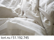 Rumpled white bedding with deep creases, displaying unmade morning bedroom atmosphere and soft comfort. Стоковое фото, фотограф Данил Руденко / Фотобанк Лори