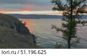 Video of Baikal Lake in evening. Silhouette of green larch trees on shore of Olkhon Island against the backdrop of colorful sunset sky. Picturesque landscape, natural background. Стоковое видео, видеограф Виктория Катьянова / Фотобанк Лори