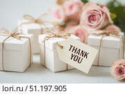 Small white gift boxes with brown string tied and a heart-shaped tag that says THANK YOU. Pink roses in the background. Wedding, special event. Party favors for guests at festive celebrations. Стоковое AI-изображение, AI-художник Марина Демидюк / Фотобанк Лори