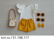 Fashion look of baby girl clothes and accessories. Set of muslin blouse, shorts, hairband and bag. Trendy cute tuff background for newborn. Toddler apparel. Female kid outfit. Pastel child wear set. Стоковое AI-изображение, AI-художник Марина Демидюк / Фотобанк Лори