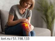 Knee pain icon. Joint pain, Arthritis and tendon problems. Woman in jeans sitting sofa, touching nee at pain point. Mature person feeling unwell, suffering from pain in leg. Red effect painful injury. Стоковое AI-изображение, AI-художник Марина Демидюк / Фотобанк Лори