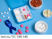 Daily pill organizer and blue awareness ribbon promoting colon cancer awareness. Стоковое фото, фотограф Дмитрий Цветков / Фотобанк Лори