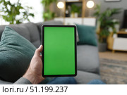 Young person holding a digital tablet with green screen in a dining room. Computer Mockup. Person using digital tablet green background display. Chroma key device. Closeup. Personal view. POV. Стоковое AI-изображение, AI-художник Марина Демидюк / Фотобанк Лори