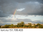 Large beautiful cumulus clouds and rainbow in evening sunset sky above golden field, summer landscape. Стоковое фото, фотограф irisff / Фотобанк Лори