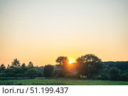 Evening sky that is clear and orange at sunset, green Russian plain with forests and gardens, and setting sun. Стоковое фото, фотограф irisff / Фотобанк Лори