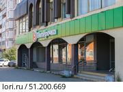 Magnitogorsk, Russian Federation - August 24, 2025: Pyaterochka store exterior view showcasing vibrant green signage and modern architecture in urban setting with clear blue sky. Редакционное фото, фотограф Ирина Ручушкина / Фотобанк Лори