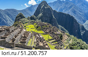 Ruins of the famous Lost City of the Incas Machu Picchu. Stone walls, dilapidated buildings, terraces with green grass. Huayna Picchu and a mountain range against a blue sky and clouds. Peru. Cusco. Стоковое фото, фотограф Вера Ивановна Кубарева / Фотобанк Лори