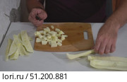 A Caucasian man is chopping zucchini with a knife on a cutting board on a kitchen countertop. Стоковое видео, видеограф Дмитрий Цветков / Фотобанк Лори