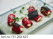 A plate of food with a variety of vegetables and a garnish of black seaweed. The dish is presented on a white plate and is arranged in a visually appealing manner. Стоковое фото, фотограф Наталия Кирсанова / Фотобанк Лори