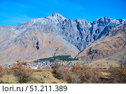 The Caucasus Mountains in Georgia and the village of Stepantsminda in the distance. The natural landscape. High peaks. The season is autumn. Стоковое фото, фотограф Наталия Кирсанова / Фотобанк Лори