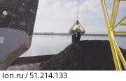 Crane loading coal onto a barge for northern delivery on the Yenisei River in daylight. Стоковое видео, видеограф Владимир Разгуляев / Фотобанк Лори