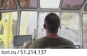 View of a young male crane operator at work in a crane cabin rear view, working professions. Crane operator manages coal loading operations from barge on Yenisei River in northern delivery. Стоковое видео, видеограф Владимир Разгуляев / Фотобанк Лори