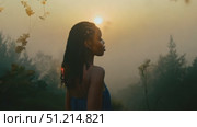 A woman stands still, gazing at the rising sun through a hazy forest, capturing the beauty of a tranquil morning filled with potential. Стоковое AI-видео, аниматор Данила Большаков / Фотобанк Лори