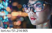 A young woman observes vibrant city lights, reflecting digital data patterns on her glasses while immersed in a technological atmosphere at night. Стоковое AI-видео, аниматор Данила Большаков / Фотобанк Лори