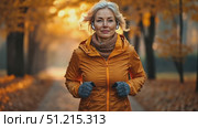 A woman in an orange jacket runs through a scenic park filled with autumn foliage, relishing the peaceful morning atmosphere and fresh air. Стоковое AI-видео, аниматор Данила Большаков / Фотобанк Лори