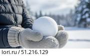 Hands in warm mittens holding perfect snowball on sunny winter day, closeup of person making snowball for fun outdoor game or snowman. Стоковое AI-изображение, AI-художник Павел Муравьев / Фотобанк Лори