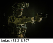 Modern soldier in combat uniform, helmet and radio headset, shooting handgun in the darkness. Oleg Zabielin / Stocktrek Images/TASS. Стоковое фото, агентство ТАСС / Фотобанк Лори