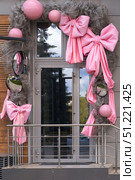 The entrance to the building is a glass door decorated with pink bows and round mirrors. The glass reflects the outline of a pine tree. Стоковое фото, фотограф Роман Дзюбало / Фотобанк Лори
