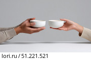 White table hosting two people swapping identical empty bowls, symbolizing sharing and minimalist exchange of interpersonal connection. Стоковое AI-изображение, AI-художник Юрий Поздников / Фотобанк Лори