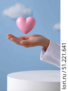 Healthcare professional wearing white coat, presenting pink heart symbol against blue sky, conveying medical empathy and humanitarian care. Стоковое AI-изображение, AI-художник Юрий Поздников / Фотобанк Лори