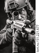 Close up portrait showing special forces soldier aiming assault rifle, wearing tactical gear, helmet, conducting operation in dimly lit tactical environment. Стоковое AI-изображение, AI-художник Юрий Поздников / Фотобанк Лори