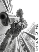Police officer wearing tactical gear and aiming a handgun during an urban operation, creating a dramatic scene of law enforcement in action. Стоковое AI-изображение, AI-художник Юрий Поздников / Фотобанк Лори