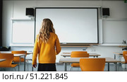 Young student in bright orange sweater walking near whiteboard in vacant classroom, pivoting and explaining academic subject with expressive hand gestures. Стоковое AI-видео, аниматор Юрий Поздников / Фотобанк Лори