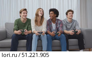 Young friends enjoying videogame session, laughing and competing while sitting together on living room sofa, holding gaming controllers. Стоковое AI-видео, аниматор Юрий Поздников / Фотобанк Лори