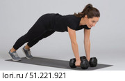 Muscular female athlete performing renegade rows with weights, balancing on fitness mat against white backdrop, demonstrating core strength during exercise training. Стоковое AI-видео, аниматор Юрий Поздников / Фотобанк Лори