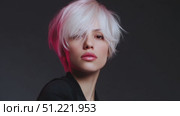 Professional model sporting platinum blonde pixie haircut with pink highlights, bathed in magenta lighting, presenting edgy contemporary hair styling against shadowy backdrop. Стоковое AI-видео, аниматор Юрий Поздников / Фотобанк Лори