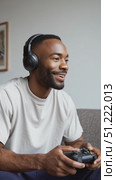 Black male gamer wearing headset, concentrating intensely while controlling game, sitting relaxed on home couch, immersed in digital entertainment experience. Стоковое AI-видео, аниматор Юрий Поздников / Фотобанк Лори
