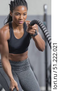 Strong female athlete using battle ropes for an intense upper body workout, demonstrating strength and determination in a fitness center setting. Стоковое AI-видео, аниматор Юрий Поздников / Фотобанк Лори