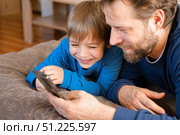 Father and son little boy laughing and using phone. They watching funny videos together, playing games on smartphone. Concept technology, smart phone addicted. Fun weekend activity. Modern fatherhood. Стоковое фото, фотограф Марина Демидюк / Фотобанк Лори