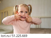 Little Girl joking sticking tongue out with silly expression. Child making face. Funny foolishness portrait of baby girl laughing in bedroom. Adorable Caucasian kid doing crazy comical gesture at home. Стоковое фото, фотограф Марина Демидюк / Фотобанк Лори