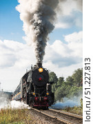 An old Soviet steam locomotive of the L series. The Ruskeala Express retro train is on its way to the mountain park. Thick smoke is coming from the chimney. Russia, Republic of Karelia, Sortavala, August 10, 2025. Редакционное фото, фотограф Photojuli / Фотобанк Лори