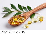 Yellow Pills in a wood spoon. Vitamin D. White background. Big golden tablets. Omega 3 capsules. Healthy every day fatty acid. Food supplement fish oil. Human health benefits product banner. Nutrients. Стоковое AI-изображение, AI-художник Марина Демидюк / Фотобанк Лори
