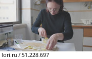 Woman arranging sliced potatoes in glass bowl in kitchen. Стоковое видео, видеограф Константин Шишкин / Фотобанк Лори